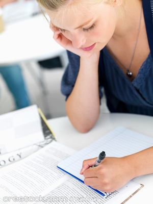 Portrait of a young woman writing notes at cla...