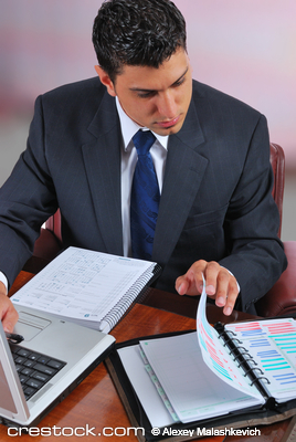 young businessman sitting at a desk, working o...