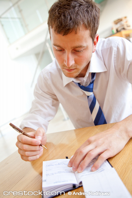 Business man writing an appointment on his agenda