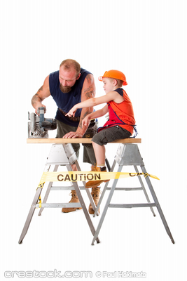 Cute son is helping dad cutting a wooden plank...